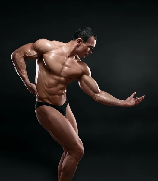 Handsome muscular bodybuilder posing over black background. — Stock Photo, Image