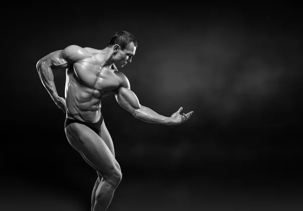 Handsome muscular bodybuilder posing over black background. — Stock Photo, Image