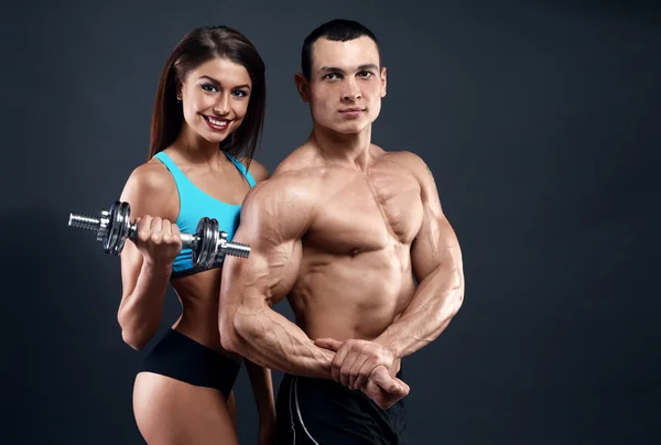 Athletic man and woman with a dumbells — Stock Photo, Image