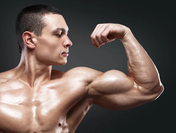 Forte e bonito jovem fisiculturista demonstrar seus músculos um — Fotografia de Stock