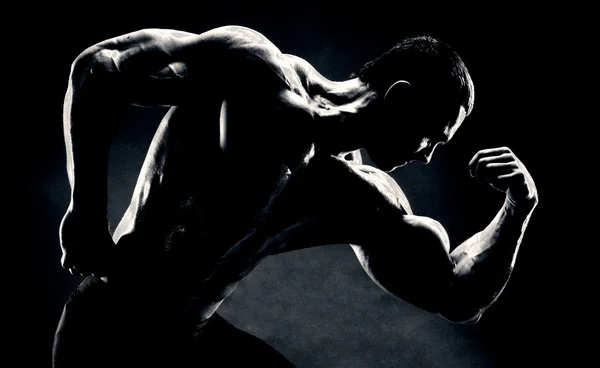 Bodybuilder demonstriert Bizeps auf dunklem Hintergrund — Stockfoto