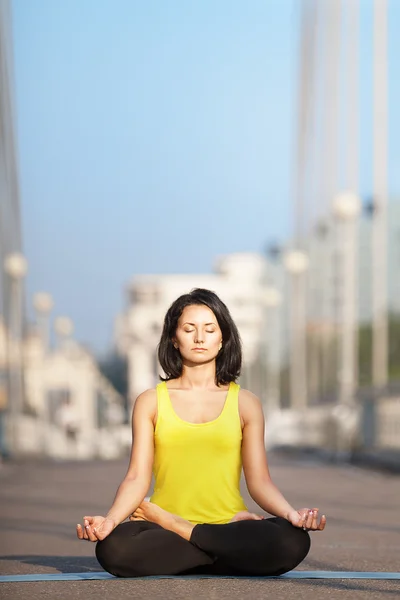 Vacker kvinna gör yoga på bakgrund av den urbana landsk — Stockfoto