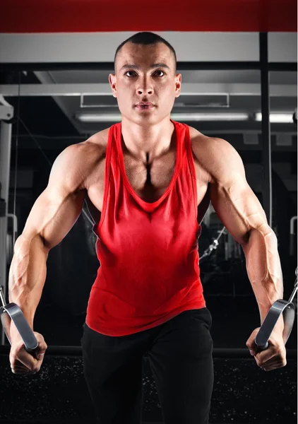 Bodybuilder pumping up muscles on crossover — Stock Photo, Image