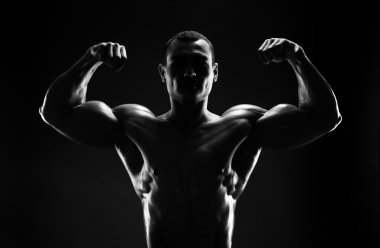 karanlık bir arka plan üzerinde pazı vücut geliştirmeci gösterir