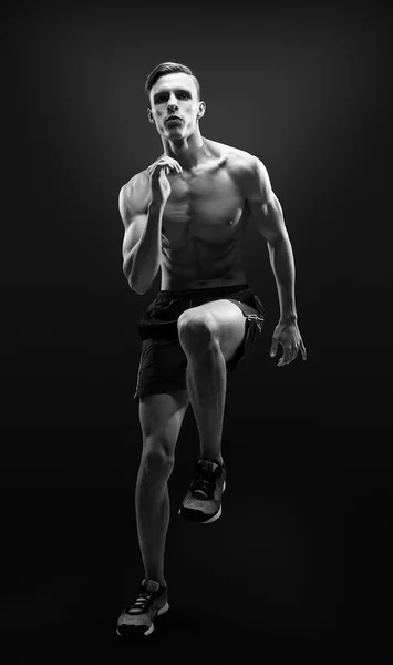 Hombre sano y fitness corriendo sobre fondo negro . Imagen De Stock