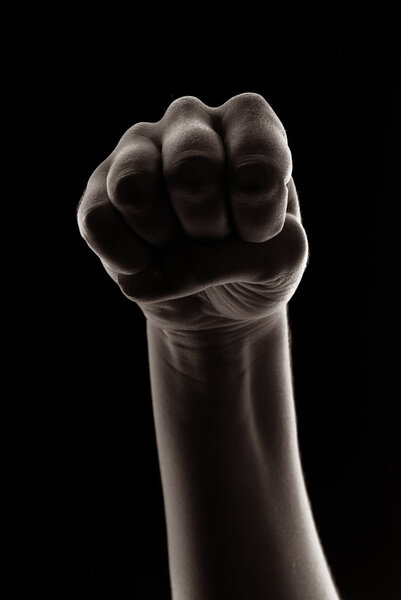 Woman hand in fist isolated on black background. Creative studio