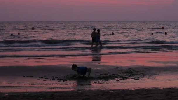 Pattaya - 07 maart 2016: Zonsondergang op het strand met silhouet van niet-geïdentificeerde mensen wandeling langs de oever. Thailand. — Stockvideo