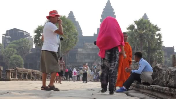CAMBODIA, SIEM REAP PROVINCE, ANGKOR WAT, MARCH 09, 2016: Unknown monk and temple worker  carry on dialogue, tourists background. Siem Reap province, Cambodia — Stock Video