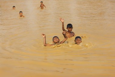 CAMBODIA, SIEM REAP PROVINCE, TONLE SAP LAKE, MARCH 13, 2016: Floating village of Vietnamese refugees on the Tonle Sap lake in Siem Reap province. Unknown children swim and play in water, Cambodia clipart