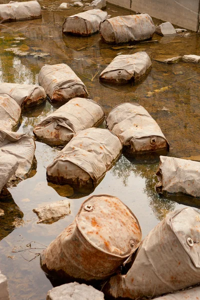 Gamla marmor stenbrottet, övergivna bränsle fat på botten. Oförsiktig inställning till naturen. Industriella restprodukter för Oljeraffinering. Utvinning av mineraler genom öppen. — Stockfoto