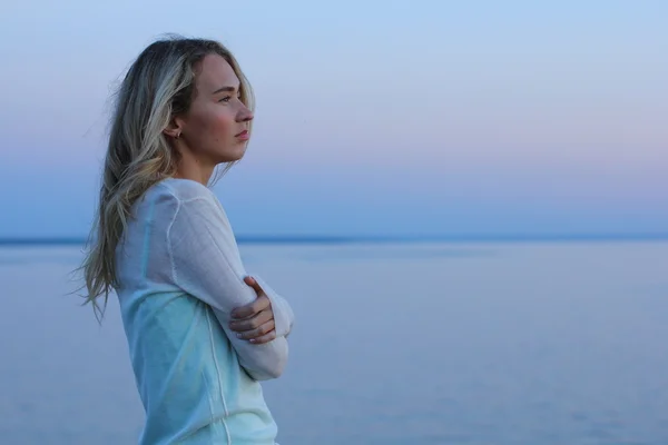 Portrait de jeune femme charmante en robe bleue se détendre tout en étant assis près de l'océan en soirée d'été, belle femme insouciante pendant les loisirs le week-end . — Photo