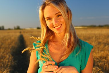 Bir kadının bir buğday alanında yakın alacakaranlıkta, altın saat. Batan güneşin.