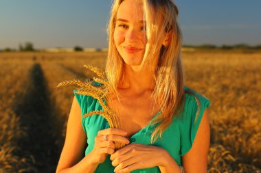 Bir kadının bir buğday alanında yakın alacakaranlıkta, altın saat. Batan güneşin.