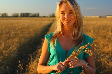 Bir kadının bir buğday alanında yakın alacakaranlıkta, altın saat. Batan güneşin.
