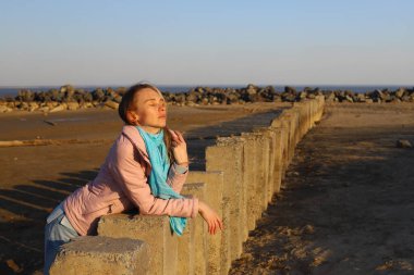 A girl in blue casual clothes walks on stones.