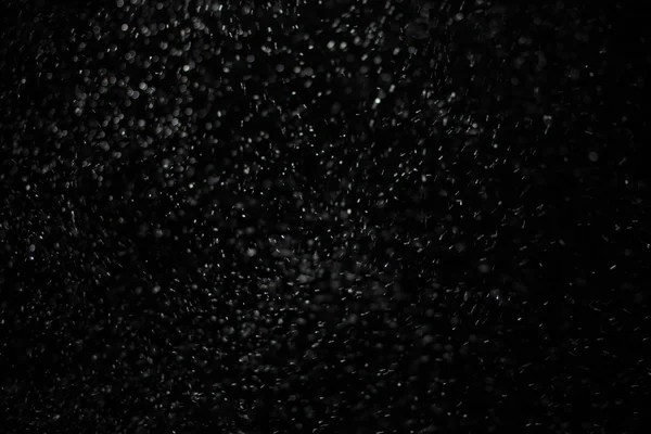 Abstrakte Schneesturmtextur. Bokeh-Lichter auf schwarzem Hintergrund, Schuss fliegender Schneeflocken in der Luft — Stockfoto