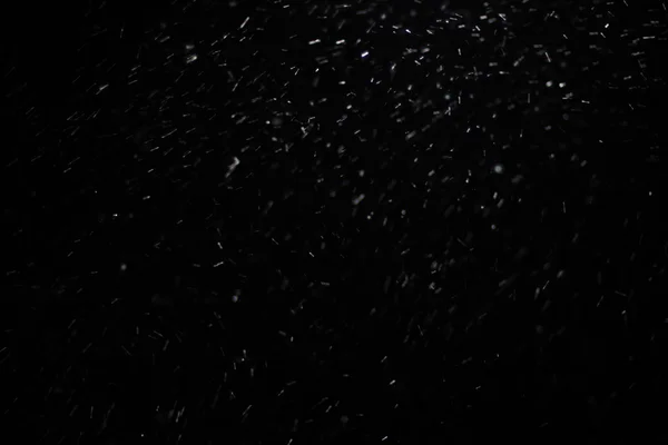 Textura abstracta de tormenta de nieve. Luces Bokeh sobre fondo negro, plano de copos de nieve voladores en el aire — Foto de Stock