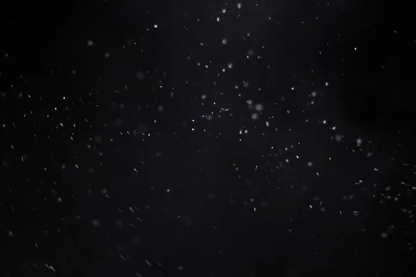 Streszczenie tekstura Kurzawa. Bokeh świateł na czarnym tle, strzał z latający płatki śniegu w powietrzu — Zdjęcie stockowe