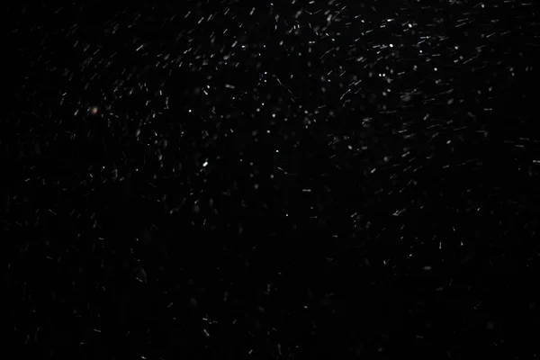Abstrakte Schneesturmtextur. Bokeh-Lichter auf schwarzem Hintergrund, Schuss fliegender Schneeflocken in der Luft — Stockfoto