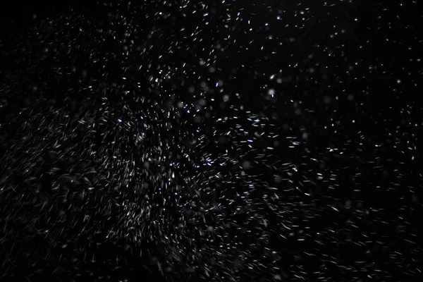 抽象的暴风雪纹理。在黑色背景上的散景灯拍摄的飞片雪花在空中 — 图库照片