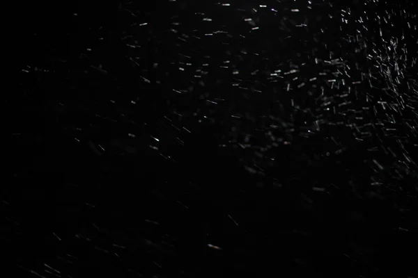 Abstract snowstorm texture. Bokeh lights on black background, shot of flying snowflakes in the air — Stock Photo, Image