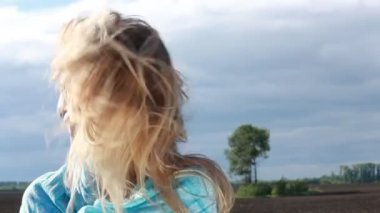 Mavi eşarp genç kadınla yaz fırtınalı alanına yürüyor.