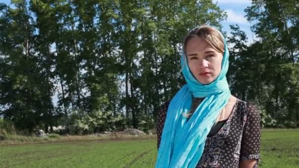 Jeune femme avec foulard bleu marche en été champ orageux . — Video