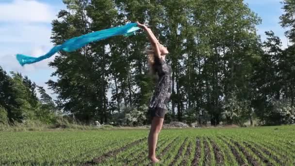青のスカーフを持つ若い女性を歩く夏嵐フィールド. — ストック動画