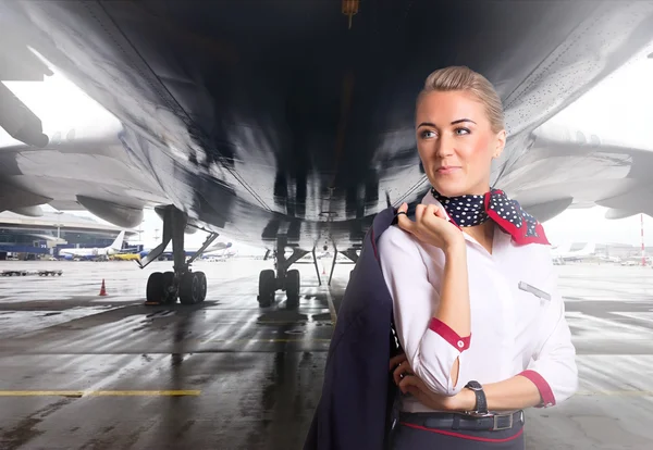 Assistente de bordo atraente perto de avião no aeroporto . — Fotografia de Stock