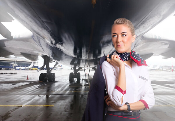 Attractive flight attendant near airplane in airport.