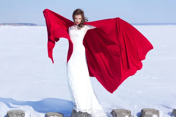 Mujer en vestido ondulante blanco con tela voladora roja Fotos de stock libres de derechos