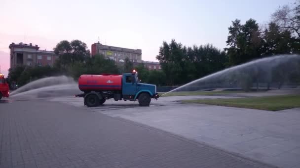 NOVOSIBIRSK russia, - JUNE 20, 2015: Lorry water cistern yang mengairi rumput di taman malam. 20 Juni 2015 di Novosibirsk Russia — Stok Video