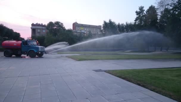 NOVOSIBIRSK Rusia, - 20 de junio de 2015: Camión cisterna de agua regando una hierba en el parque nocturno. 20 de junio de 2015 en Novosibirsk Rusia — Vídeo de stock