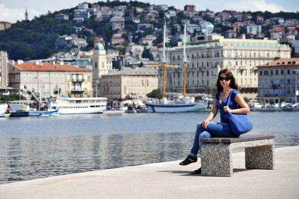 Belle femme assise sur un banc dans le port Images De Stock Libres De Droits