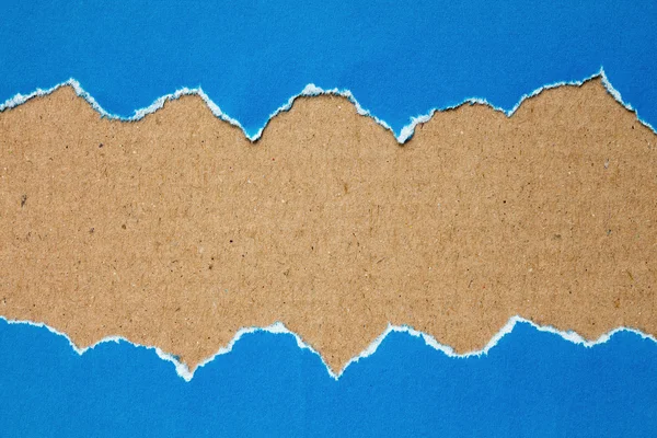 Torn blue paper with a cardboard — Stock Photo, Image