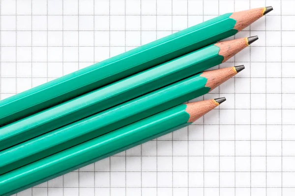 Cuatro lápices sobre papel cuadrado —  Fotos de Stock