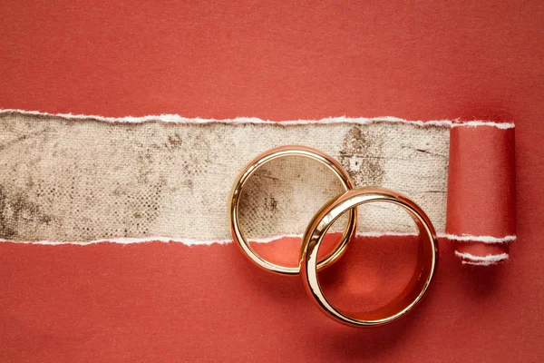 Papier rouge déchiré et bagues de mariage — Photo