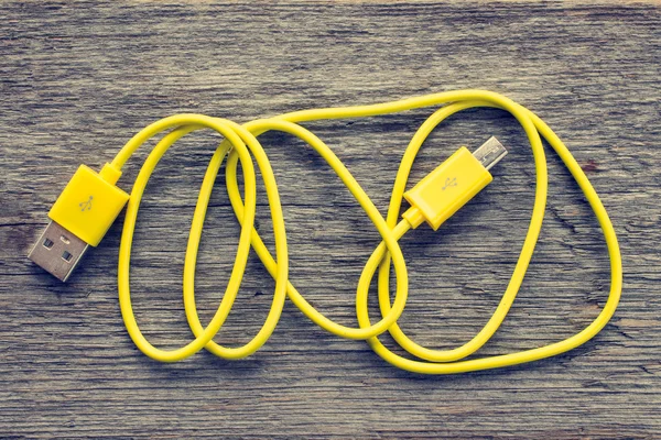 Yellow USB cable on wooden table — Stock Photo, Image