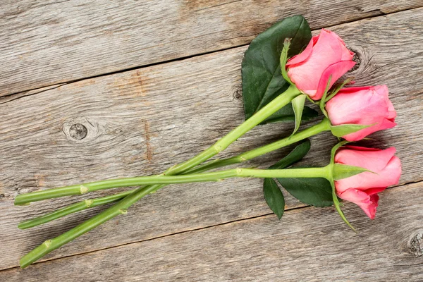 Drei rosa Roseson hölzernen Hintergrund — Stockfoto