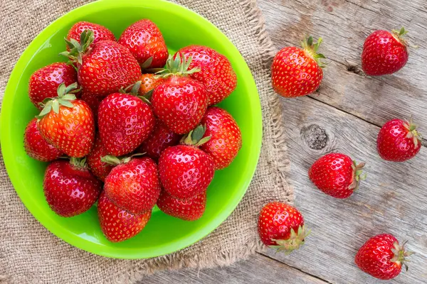 Green plate with red strawberries — Stock Photo, Image