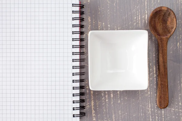 Branco tigela com colher e caderno em branco — Fotografia de Stock