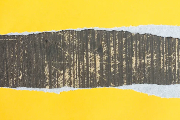 Papel rasgado de amarelo com um fundo de madeira — Fotografia de Stock