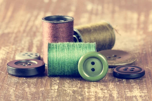 Spools of thread and buttons on wooden background — Stock Photo, Image