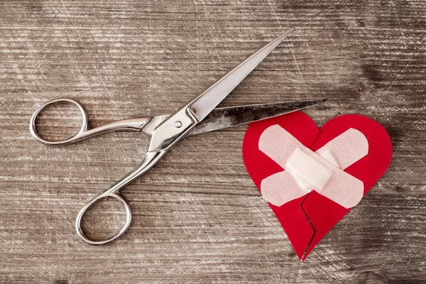 Розбите серце з пов'язкою і ножицями — стокове фото