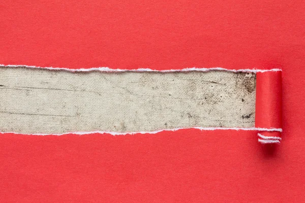 Torn red paper on dirty canvas. — Stock Photo, Image