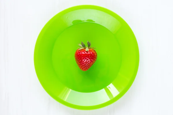 Fresh single strawberry in green plate — Stock Photo, Image