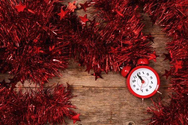 计算圣诞节或新年前的最后一刻 倒计时到午夜红色的闹钟在明亮的花环中躺在桌子上 叮当作响 — 图库照片