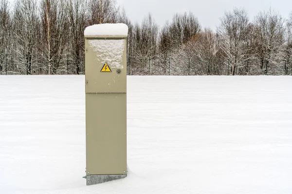 Outdoor Electric cabinet on the snow field. Metal electric cabinet in the nature in the snowdrift.