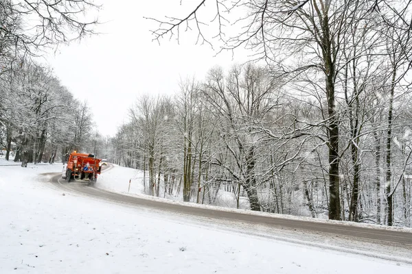 下雪时 铲雪卡车扫清了穿过森林的道路 — 图库照片