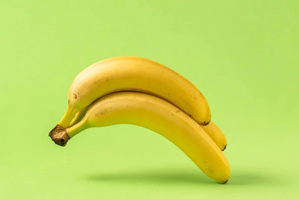 Ett Gäng Gula Bananer Leviterar Grön Bakgrund — Stockfoto